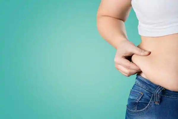 Image of woman pinching her love handles to show weight gain Heath